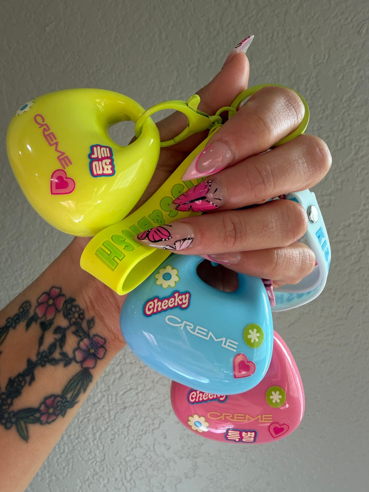 A manicured hand holding colorful sticker-decorated Kiss & Blush compacts