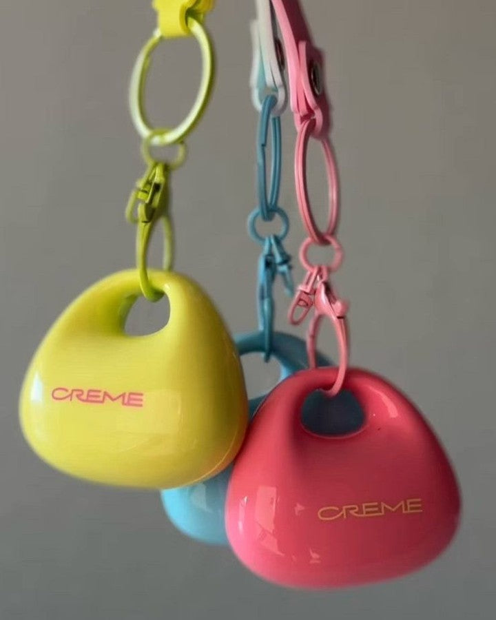 Yellow, aqua and pink Kiss & Blush compacts hanging from matching clips